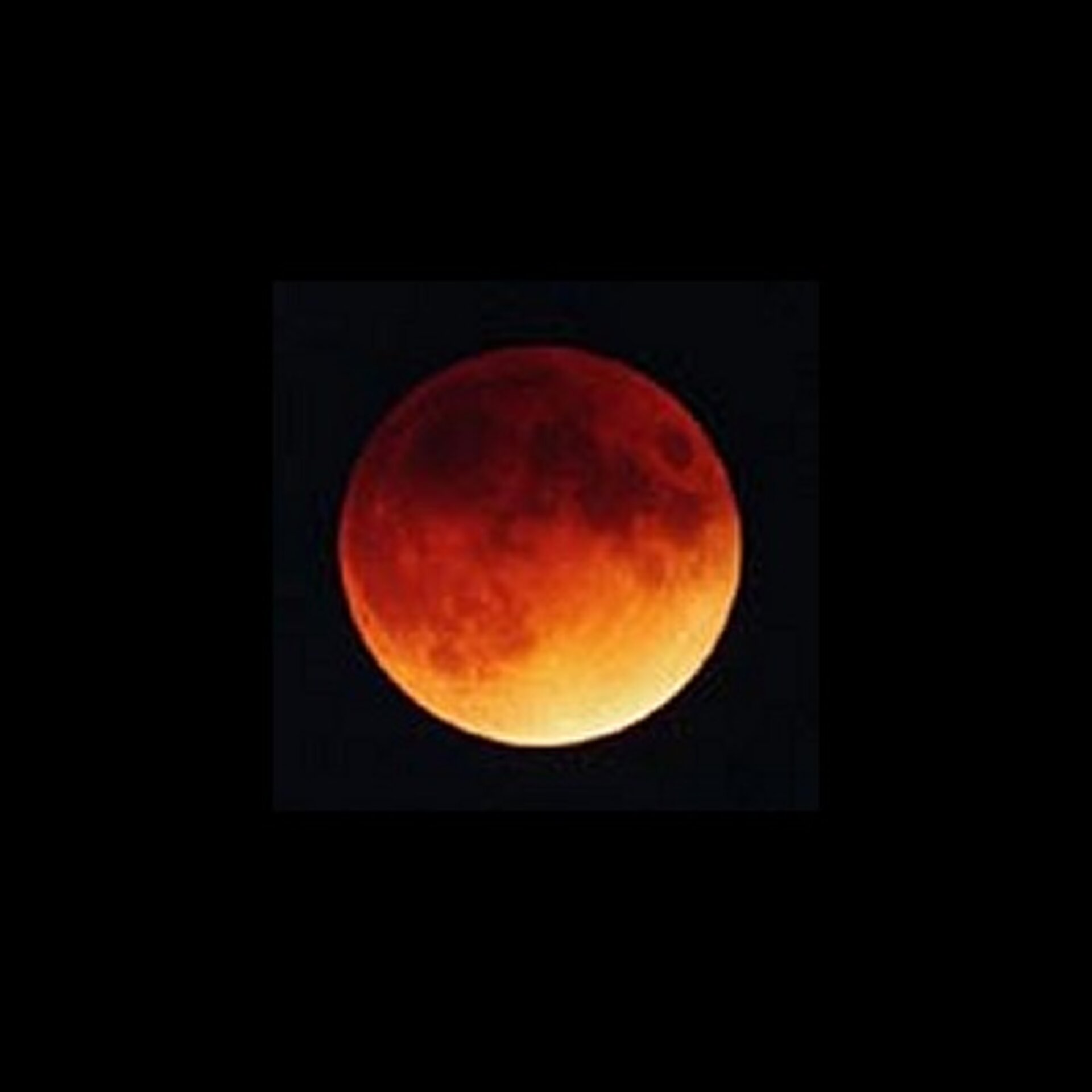 De  totaal verduisterde maan straalt met een oranje-rode gloed